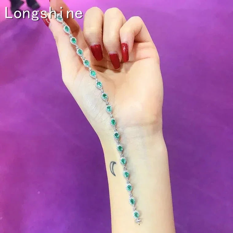 Elegant 18K gold emerald diamond bracelet displayed on wrist with purple background