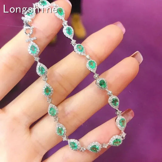 18K gold emerald diamond bracelet with pear-shaped emeralds and sparkling diamonds held in hand